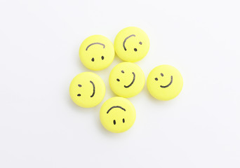 Pills with drawn happy faces on white background