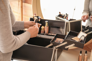 Professional makeup artist with set of decorative cosmetic in case