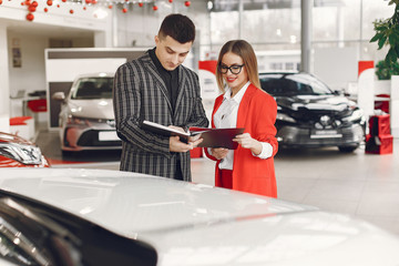 Couple in a car salon. Family buying the car. Elegant woman with her boyfriend.