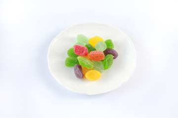 Colourful gummy sugary candy on a white plate.
