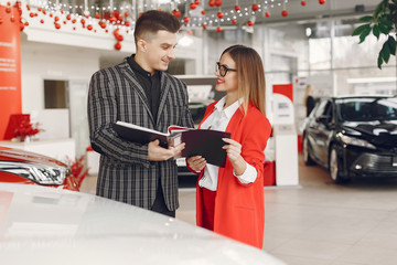 Couple in a car salon. Family buying the car. Elegant woman with her boyfriend.