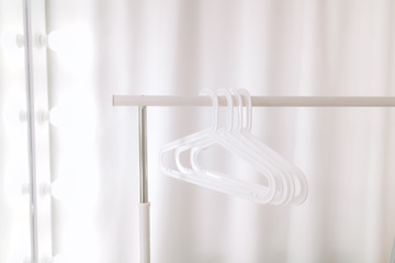 Stylish white hangers on a white counter in a white room