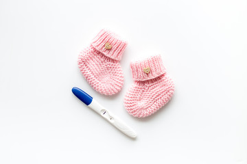 Positive pregnancy test. Baby girl concept with pink booties on white background top-down