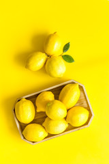 Ripe lemons in tray on yellow backgroud top-down