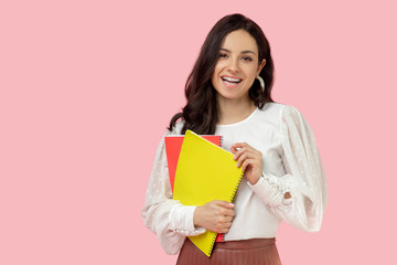 Young woman in a white blouse holding notebooks and looking contented