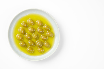 pitted green olives in olive oil, white background top view, closeup