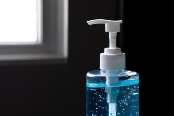 Blue hand sanitizer gel in clear pump bottle with black background, that use for killing germs, bacteria and viruses. Prevent the spread of germs and bacteria and avoid infections corona virus.