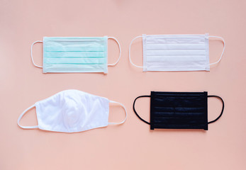 Flat lay of various kind and color of hygienic masks on bright pastel peach orange color...