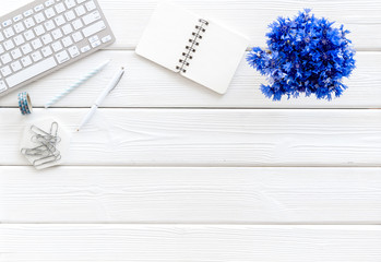 Summer vibes at work. Office desk with cornflowers bouquet on white wooden background top-down frame copy space