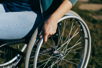Close up of a young woman in a wheelchair while walking in a park on a sunny day. Recovery and...
