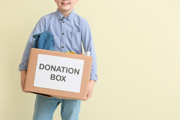 Little boy with donations on color background