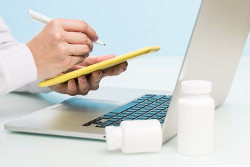 Doctor's hand uses a laptop and digital tablet on a blue background. medicine concept, modern technology