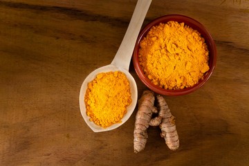 Turmeric powder and roots on a dark wooden surface