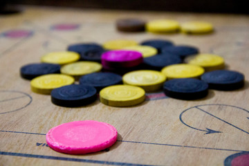 A game of carom set and ready to play. A game of carrom with pieces carrom man on the board carrom. Carom board game, selective focus.