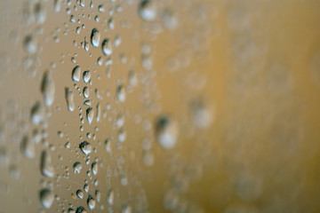 close up rain drops on my window with a golden background 