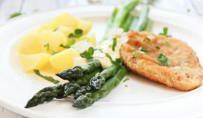 Teller mit grünerm Spargel Tisch Schnitzel und Kartoffeln