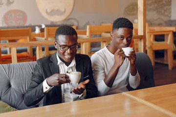 Black men in a cafe. Guys drinking a coffee. Businessman in a black suit.