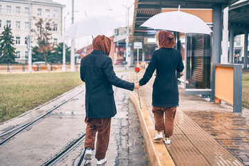 young couple walks along the road in the rain. man and woman under umbrella in bear costumes