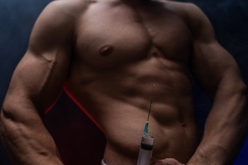 Bodybuilder holding big syringe with injection. concept of steroid in the sport and addiction 