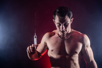 Bodybuilder holding big syringe with injection. concept of steroid in the sport and addiction 