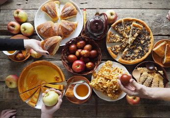 A festive set table with abundant food, pies, eggs, homemade cakes and cutlets.Hands of guests over the table. Meeting friends.