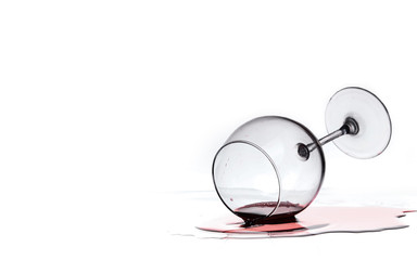 wine glass with red wine lies on glass on white background