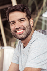 Smiling young traveler looking at camera. Cheerful handsome young man sitting near luggage at airport. Travel concept