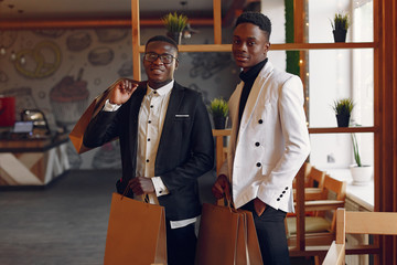 Black men in a cafe. Guys with shopping bag. Businessman in a black suit.