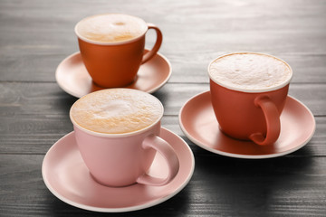 Cups of hot coffee on wooden table