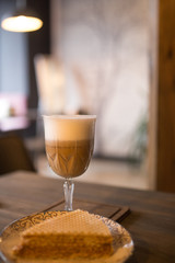 Cappuccino and a slice of cake on a table in a cafe.