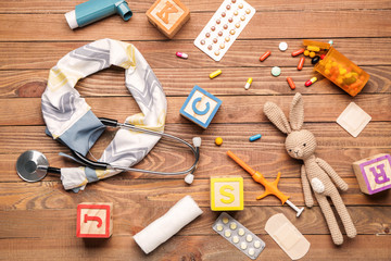 Stethoscope with cover, toys and supplies on wooden background