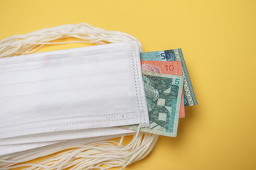 A pile of face mask with Malaysian money isolated over yellow background. Concept during Corona virus outbreak in Malaysia, shortage of face mask increase the demand in higher price.