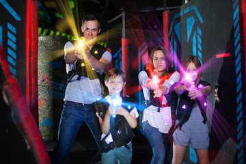 Obraz na płótnie Canvas Parents and children playing laser tag in beams