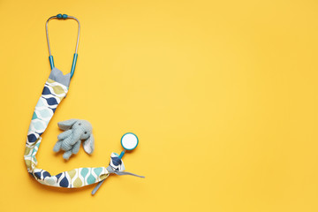 Stethoscope with cover and toy on color background