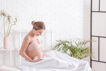 Naklejka na ściany i meble Young pregnant woman resting in spa salon