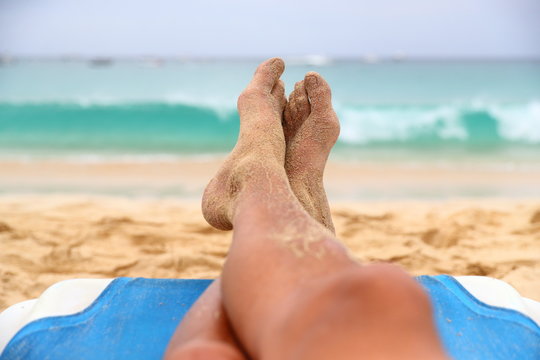 mens legs and feet resting on a beach chair portraying relaxation on holiday