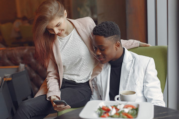 Black man in a cafe. International people. Man in a black suit. Woman in a pink jacket.
