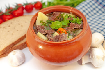 Roast in a pot with beef meat and potatoes on the table