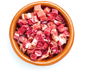 Iberian ham (serrano) cut into cubes (diced). In clay bowl. Isolated on white background.