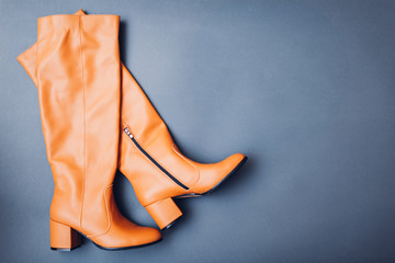 Shoes, stylish leather boots for women. Female winter, autumn or spring fashion. Orange caramel footwear. Space