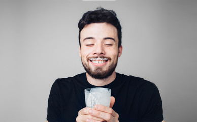 Young man isolated over background. Happy satisfied man hold glass with sour milk and smile. After drinking good meal. Smiling with eyes closed.