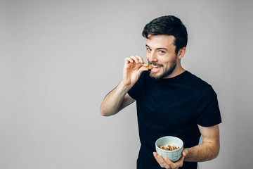 Young man isolated over background. Side view of handsome guy biting walnut and posing on camera....