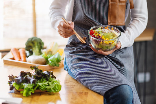 Closeup image of a woman cooking and holding a bowl of fresh mixed vegetables salad to eat in kitchen