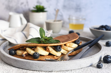 Thin crepe and banana and blueberries for breakfast on the kitchen table.