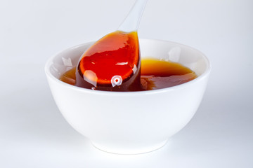 honey dripping from ceramic spoon to ceramic bowl