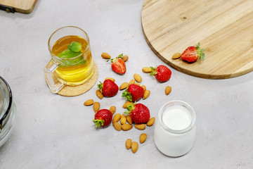 Fresh milk on the table next to fresh strawberries, almond and warm herbal tea. Morning in the...