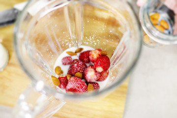Blender top view. It contains strawberries, almond and milk. The process of making a delicious smoothie. Close up.