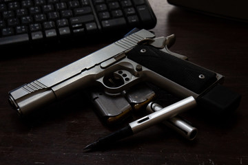 Handgun and pen on the desk. Gun .45 cal ACP model 1911 .