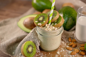 Fresh smoothie made of kiwi, avocado, oatmeal and skim milk near a burlap towel. Decorated on top. Morning meal in the village with fresh ingredients.