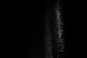 Fototapeta na wymiar White dust similar to flour and snow is actively scattered isolated on black background